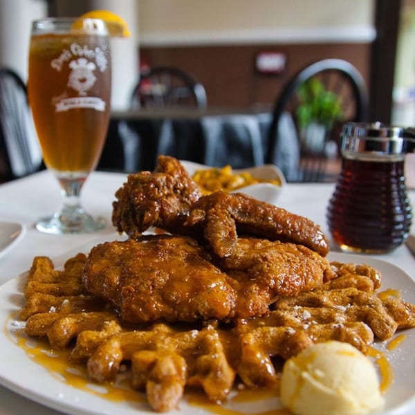 Dame's Chicken & Waffles: golden fried chicken and waffles with syrup, a scoop of butter, and iced tea.