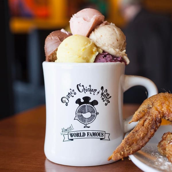 Dame's Chicken & Waffles mug filled with scoops of colorful ice cream next to fried chicken.