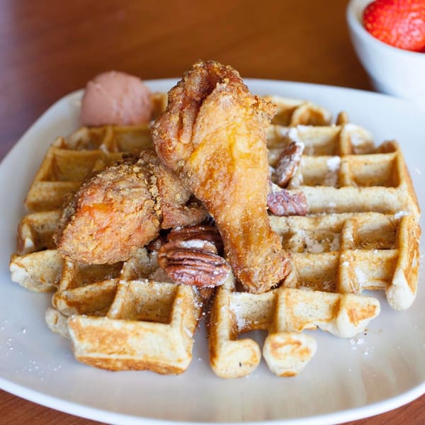 Dame's Chicken & Waffles' fried chicken and waffles, topped with pecans and a scoop of pink butter.