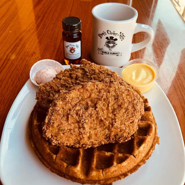 Dame's Chicken & Waffles plate with fried chicken, waffle, maple syrup, and sauces.